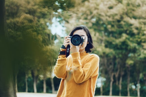 A girl is capturing a picture through her camera.