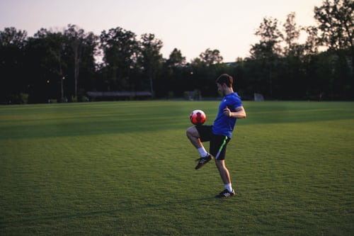 A boy practicing football in an open field